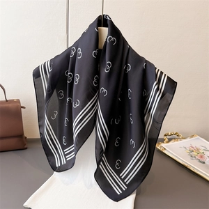 Elegant black silk scarf with geometric ring patterns draped on a mannequin