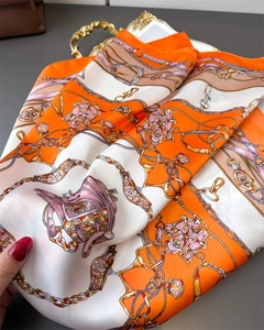 Macro detail of silk scarf featuring classic chain and buckle equestrian pattern print