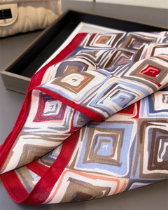 Macro detail of geometric silk scarf showing navy patterns and red rolled hem craftsmanship