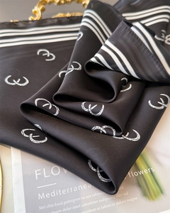 Detail of silk-like scarf featuring horsebit prints and elegant black and white stripes