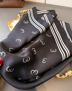 Detail of black silk scarf with white horseshoe pattern and gold decorative tray