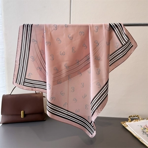 Detail of silk-like pink scarf with horseshoe patterns hanging on a metal rack
