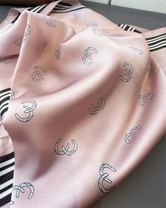 Detailed view of the smooth satin silk texture and geometric horseshoe pattern on scarf