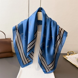 Blue faux silk square scarf with geometric chain prints and striped edges on a mannequin