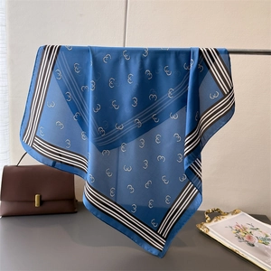 Detailed view of royal blue silk scarf with geometric print and striped border