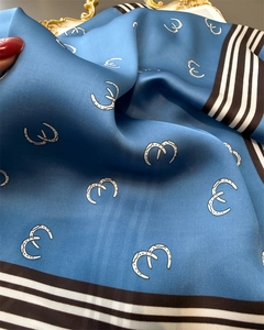 Macro detail of silk square scarf featuring blue horsebit print and elegant satin texture