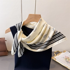 Close-up of geometric silk-like scarf with black horseshoe print and striped border edge