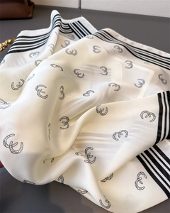 Close-up of silk scarf with geometric horse-shoe prints and striped borders