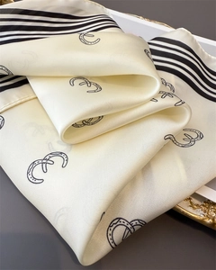 Detail of silk-like satin scarf featuring equestrian patterns and black striped edges