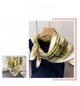 Close-up of green silk scarf with forest and bird print draped on a display model