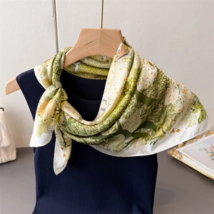 Silk-like square scarf featuring green forest and deer prints on a stylish blue vest