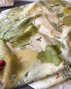 Detailed view of forest theme silk scarf with deer and peacock illustration print