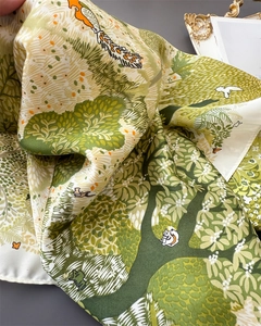 Close-up detail of forest print silk scarf showing green trees and wildlife patterns