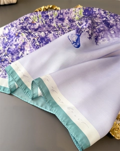 Macro shot of silk scarf detailing lavender print, blue butterfly and mint green border