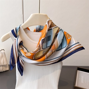 Silk-like geometric print square scarf with blue and orange patterns on a white vest