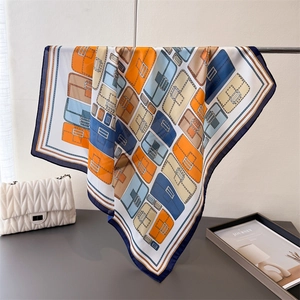 Close-up of silk scarf with colorful bag patterns hanging on a metal stand