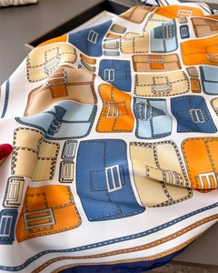 Detailed view of silk scarf with colorful vintage handbag prints and smooth satin texture