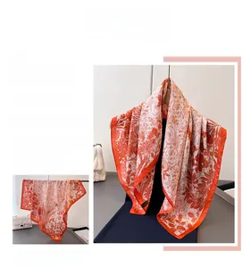 Detailed botanical print on orange silk scarf showing vibrant floral patterns and edges