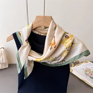 Close-up of elegant silk scarf featuring yellow floral patterns and green borders