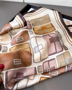 Close-up of elegant satin scarf with vintage handbag and belt prints in warm tones