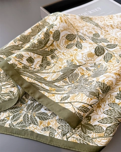 Detail of floral print silk scarf in olive green and gold showing luxurious satin texture