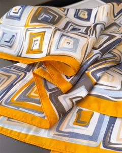 Macro shot of geometric print silk scarf with yellow and blue squares and fine stitching