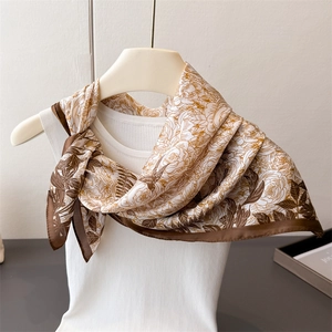 Detailed view of floral silk scarf with bird prints in coffee and beige tones