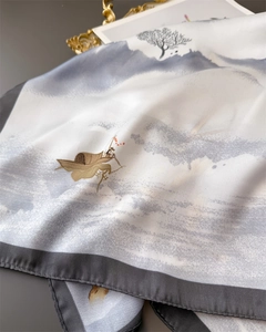 Close-up of ink landscape pattern on white silk scarf with refined grey stitched edges