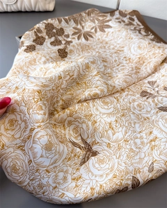 Close-up of silk-textured floral scarf featuring elegant golden-brown birds and petals