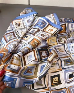 Detail of silk-like scarf showing geometric pattern in blue and brown with rolled edges