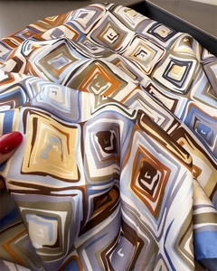 Macro shot of geometric print silk scarf showing soft texture and glossy finish