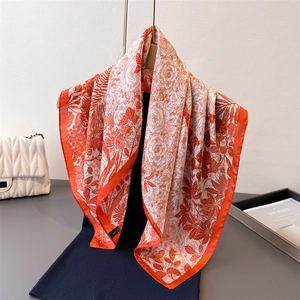 Floral satin scarf with orange flower patterns and solid border draped on dark clothing
