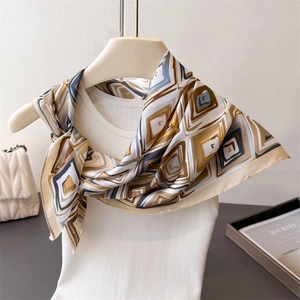 Elegant geometric print silk-like square scarf in earth tones displayed on a white top