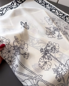 Detailed view of floral and butterfly patterns on lightweight white silk scarf