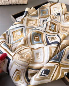 Close-up of geometric silk scarf with brown and blue patterns in a premium gift box