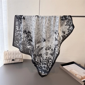 Detail of silk-like square scarf featuring elegant black and white botanical and bird prints