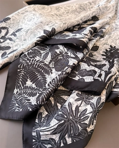 Detail of silk-like scarf featuring elegant black floral prints and smooth satin texture