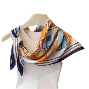 Elegant geometric print silk scarf in orange and blue worn over a white ribbed top