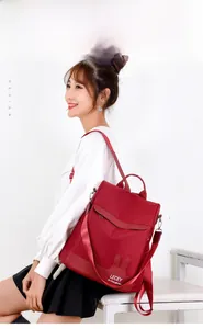 Side view of red nylon backpack with rabbit ear pockets and multi-way shoulder straps