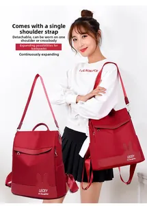 Detail of red nylon backpack showing detachable shoulder strap and versatile carrying modes