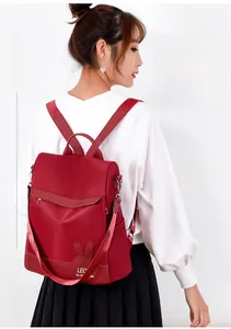 Detail of red water-resistant nylon backpack with rabbit ear decor on white background
