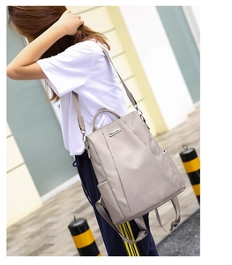 Outdoor street view of a light grey waterproof oxford anti-theft backpack with side pockets