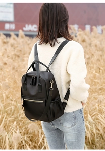 Outdoor shot of a black waterproof nylon backpack for women with gold zippers