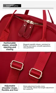 Detail of red oxford backpack showing golden dual zippers and adjustable woven straps