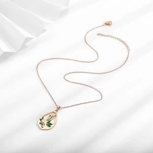 Détail du pendentif en goutte avec motif floral et zircons verts de forme marquise