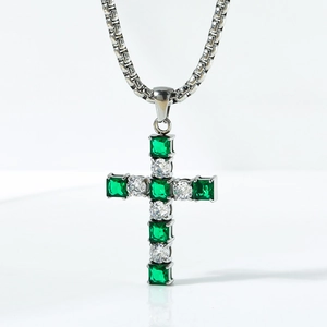 Detail of square green emerald and white zircon cross pendant on a steel chain