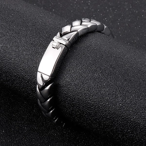 Detailed close-up of silver wheat link bracelet on black textured cylindrical display