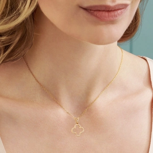 Close-up of gold-plated clover pendant necklace with paved zircon crystals on a model