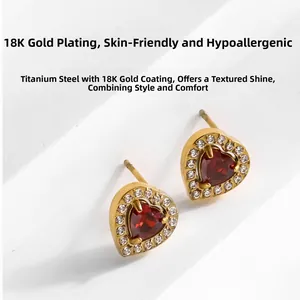 Détail de boucles d'oreilles cœur en acier doré avec pierre rouge et halo de zircon