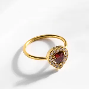 Détail d'une bague avec pierre rouge en forme de cœur et halo de zircone dorée